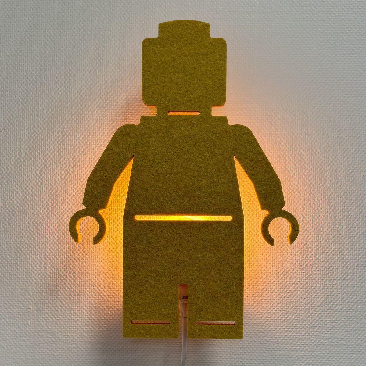 Vilten wandlamp poppetje okergeel – lamp aan